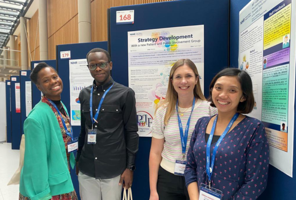Members of the NIHR King's CRF standing in front of a Patient and Public Involvement poster about the PPI strategy