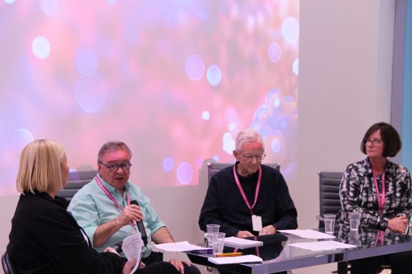 Four people sitting in front of a table with one person holding a microphone