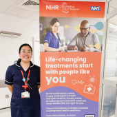 Michelle standing next to a large 'Be Part of Research' banner
